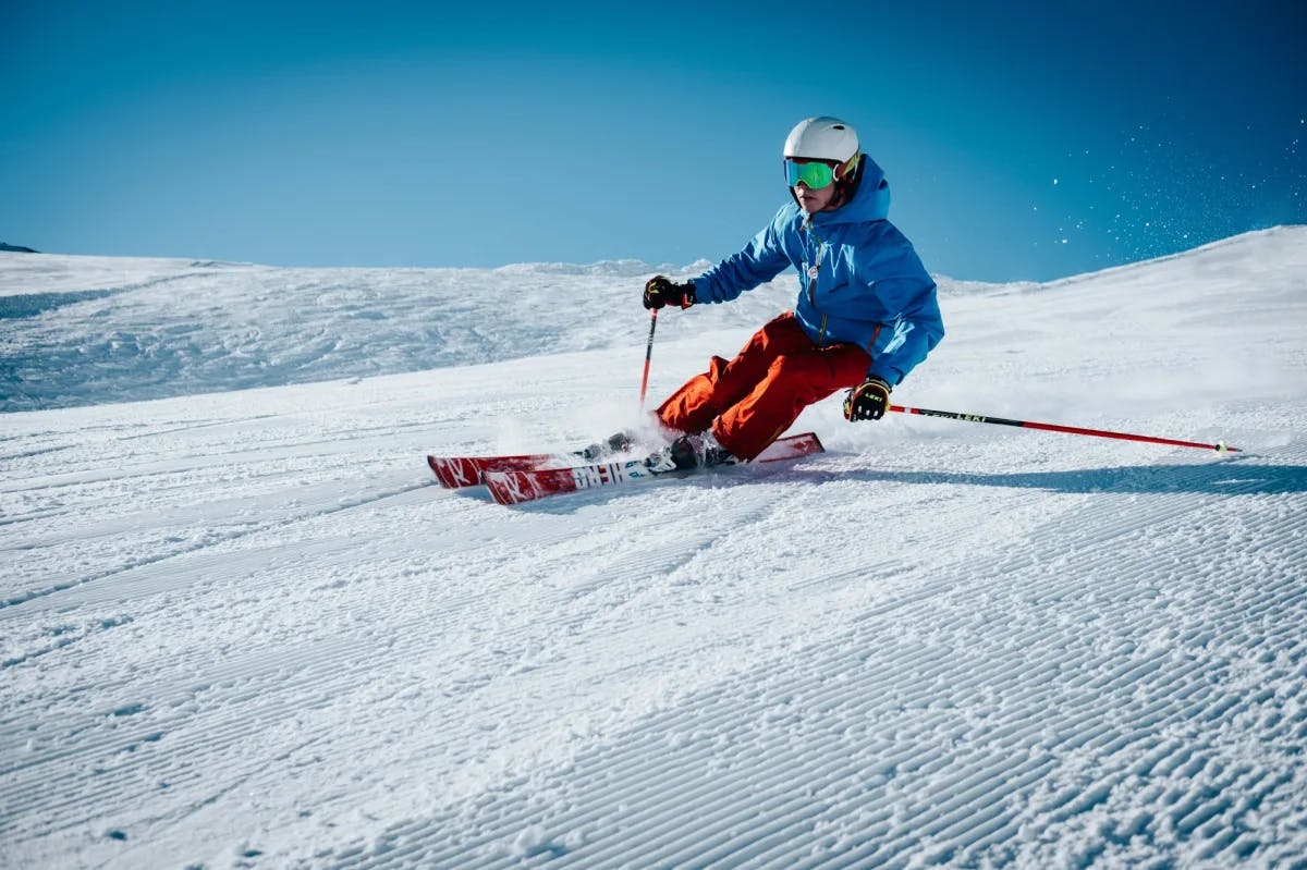 An action shot of a person skiing down a hill on a sunny day. 