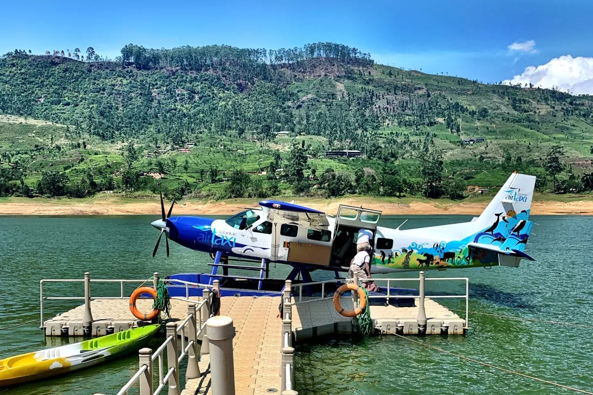 Seaplane parked at a dock with a mountain in the background. 