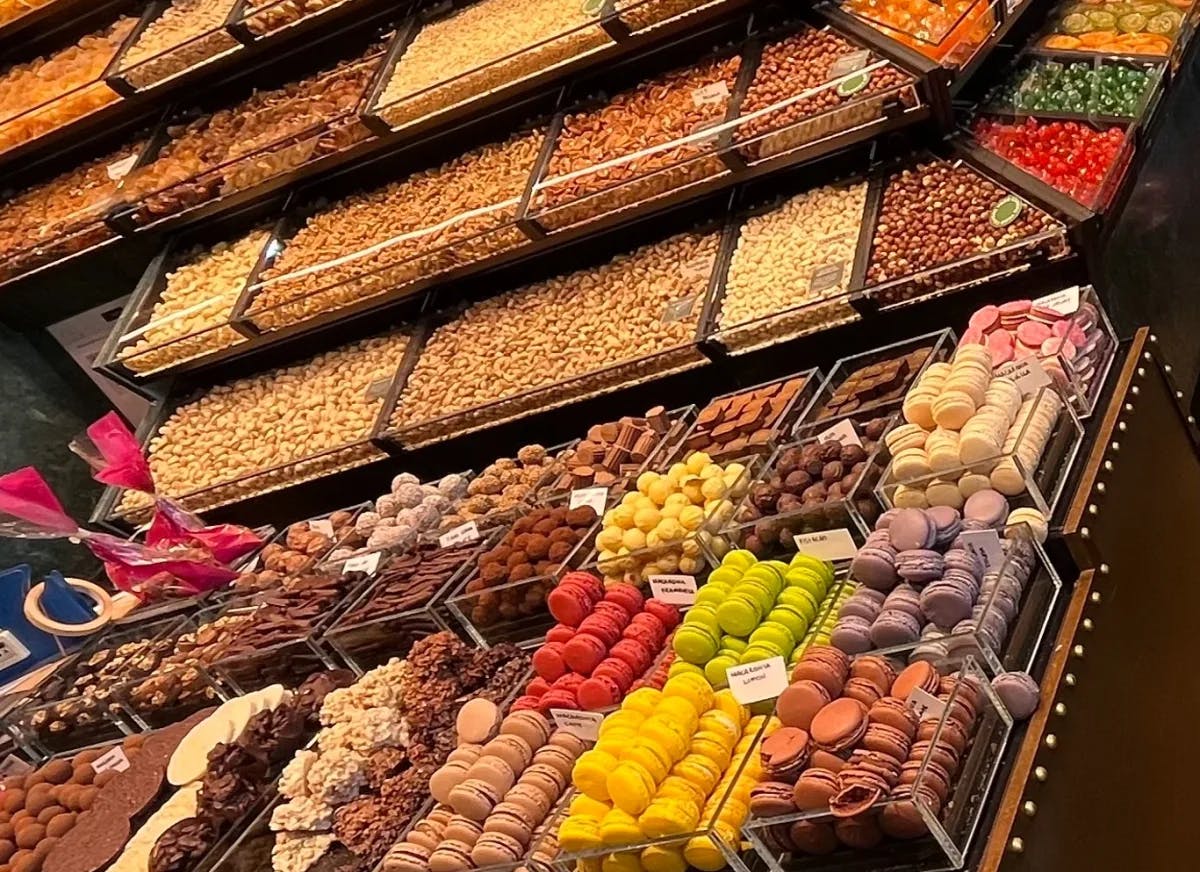 The image showcases a variety of chocolates and sweets, highlighting the diversity and presentation in a store setting.