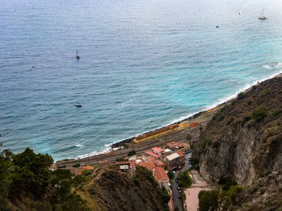 A city at the bottom of a mountain, along the coastline of the ocean.