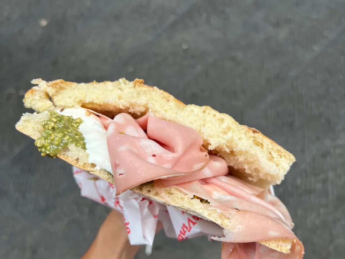 A woman's hand holding meat panini.  