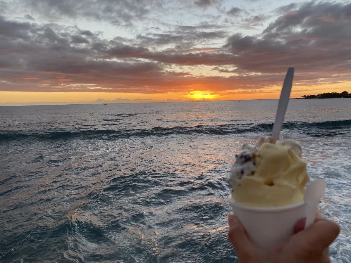 A person having icecream in the sea during sunset