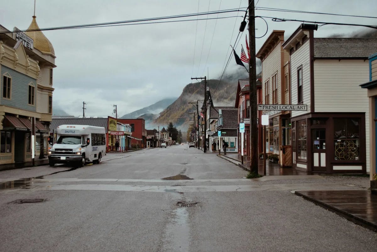 The quiet port town of Skagway, with quaint single-story buildings along a wide street next to mountains.