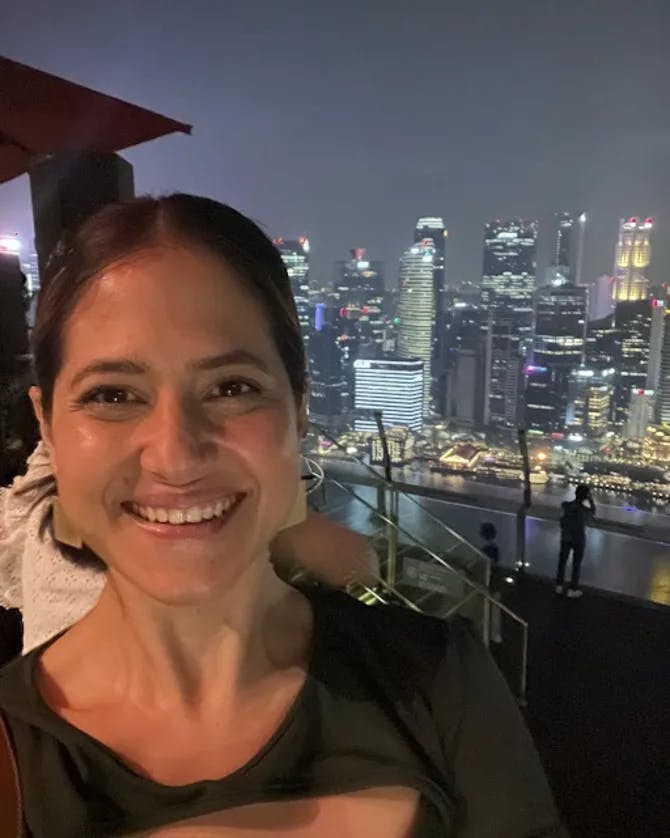 Mariela posing for a selfie in front of the Singapore skyline at nighttime