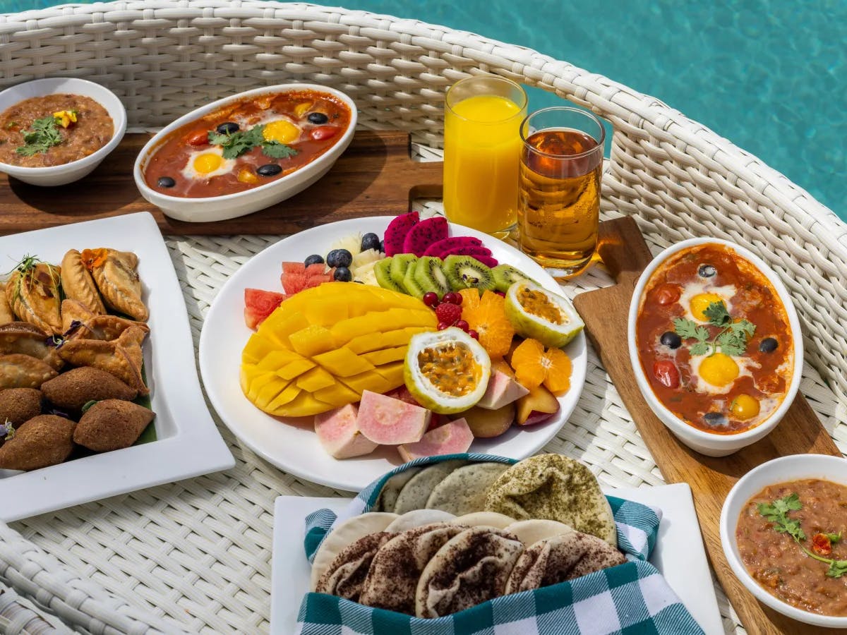 A poolside wicker tray presents a variety of dishes and drinks, offering a taste of leisure and refreshment.