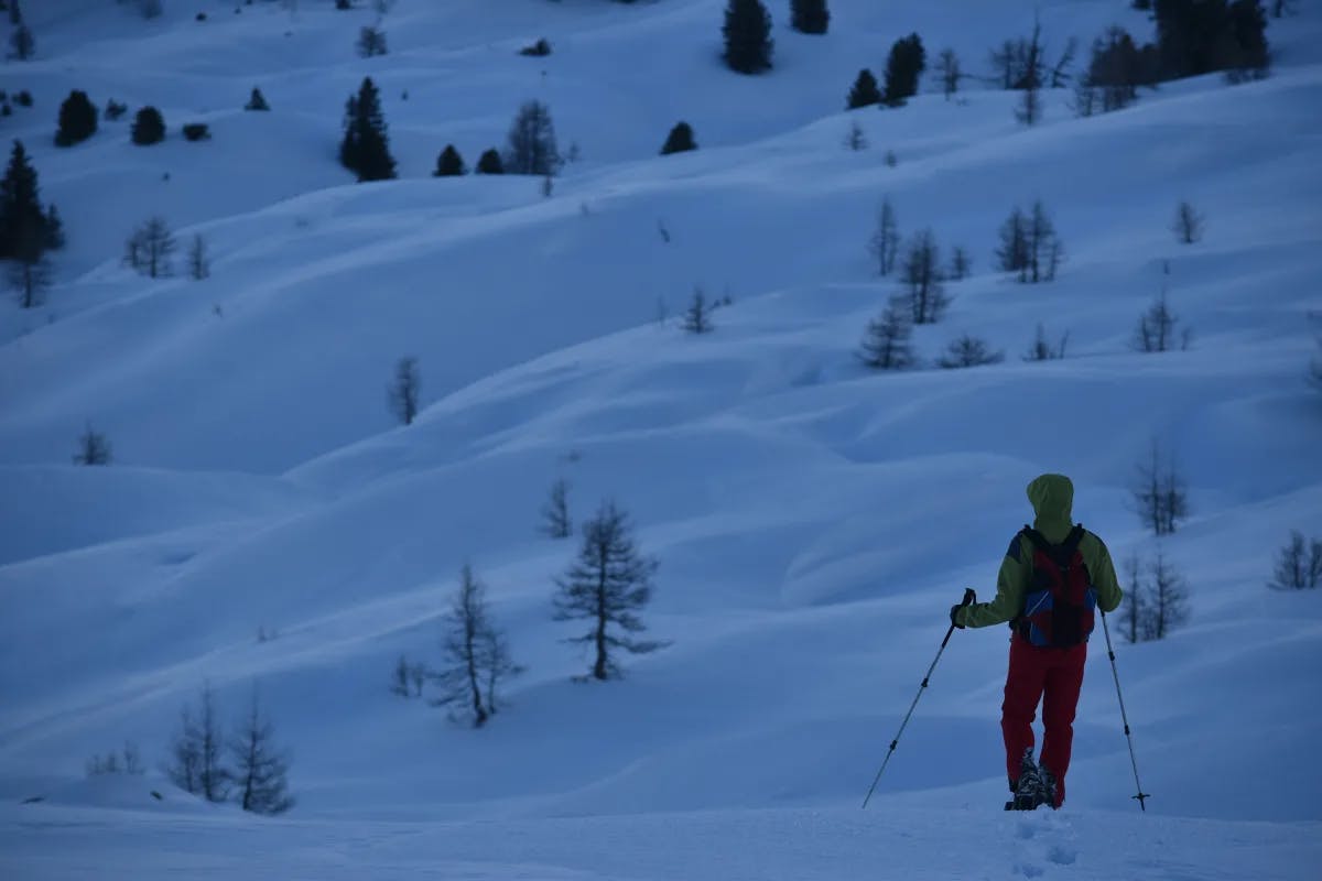 Person walking with ski poles on a snow-covered mountain
