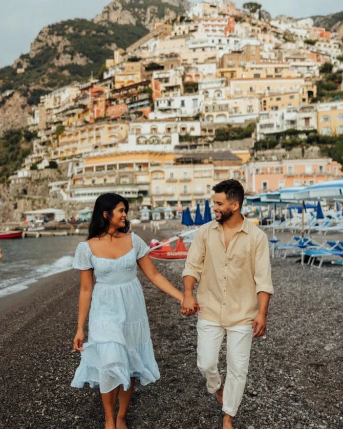 A man and woman walking on a beach holding hands. 