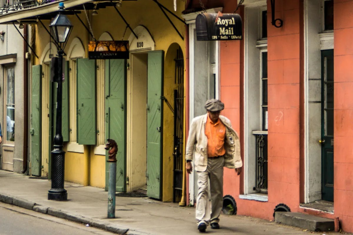 A man walking by pastel-colored buildings in the French Quarter, New Orleans