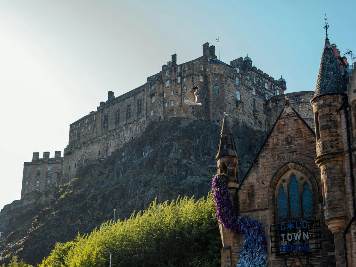 The image showcases a majestic castle atop a rugged hill, under a partly cloudy sky.