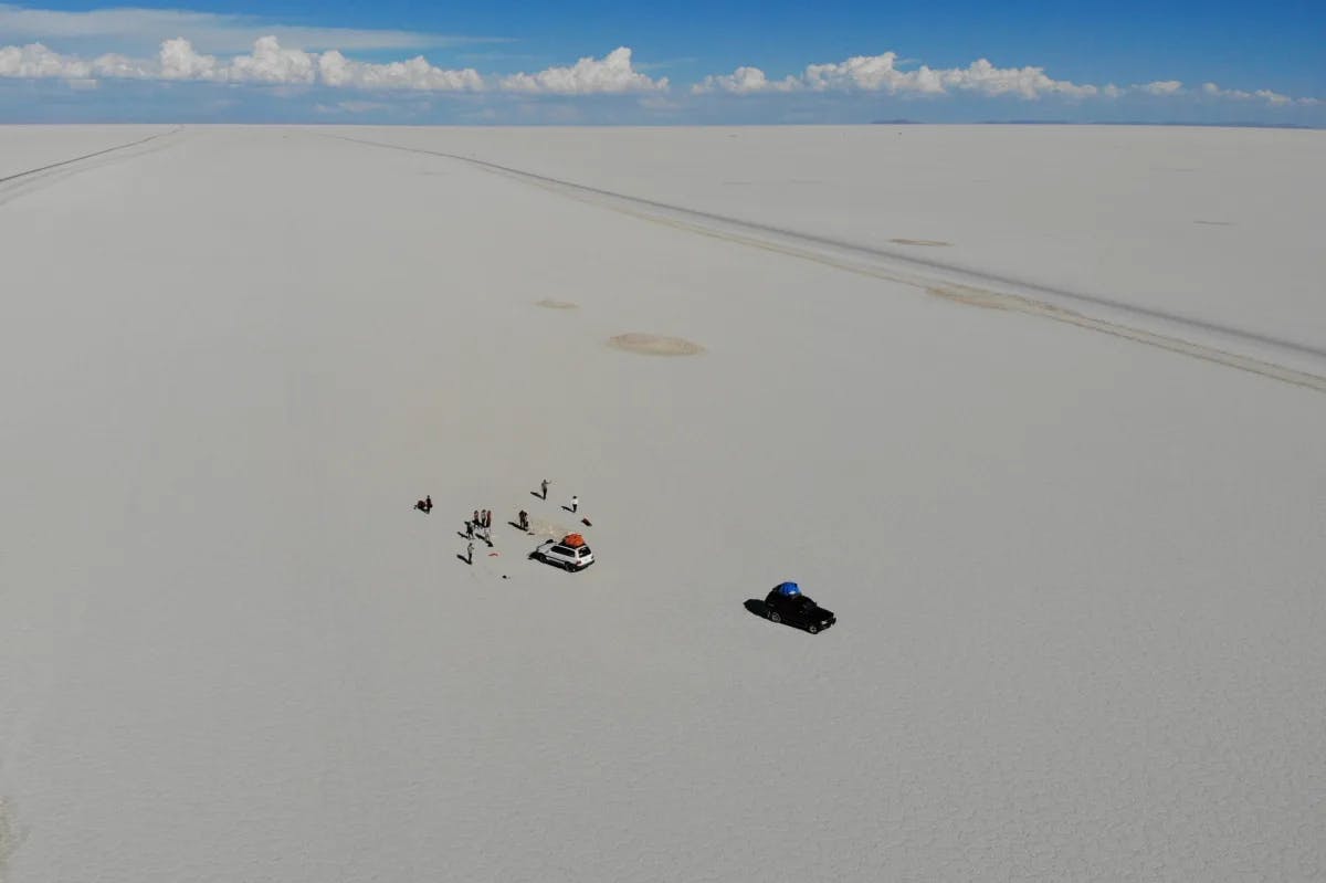 An aerial view of a Salt flat with people in vehicles in the middle of the salt flat.