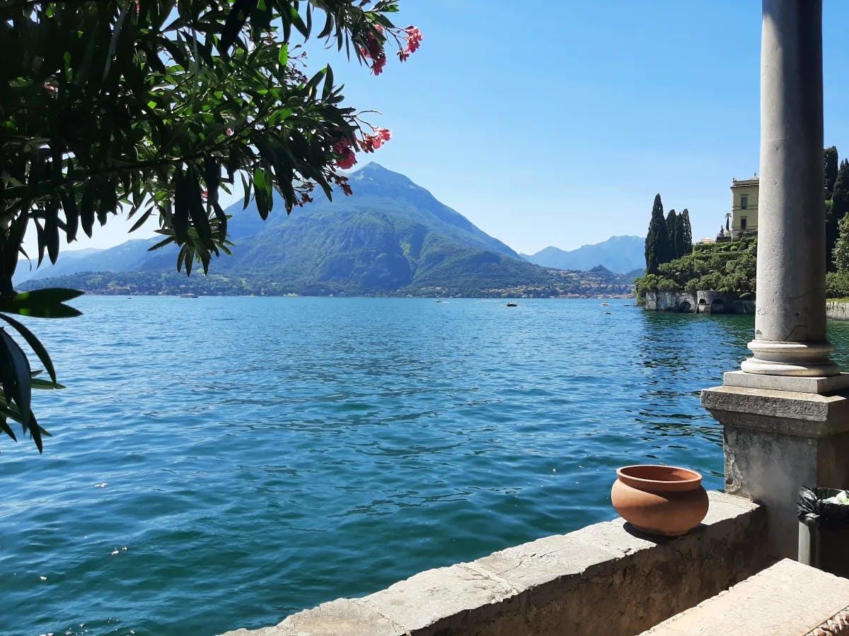 A view of the lake with trees, a pot and mountain in the background.