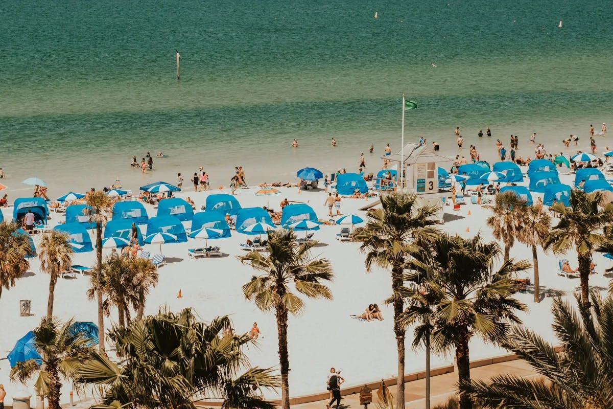 An aerial view of a beach with blue umbrellas during daytime