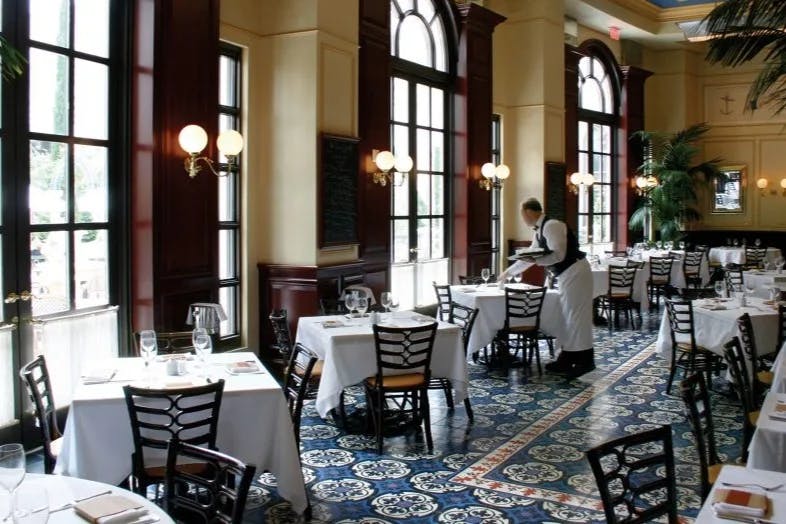 The elegant dining area of Bouchon at The Venetian with white table cloths and patterned floor.