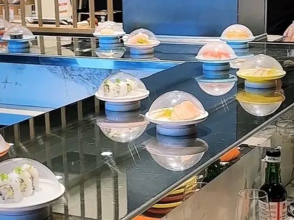 A counter top full of food on platters with a white dome on top of them. 