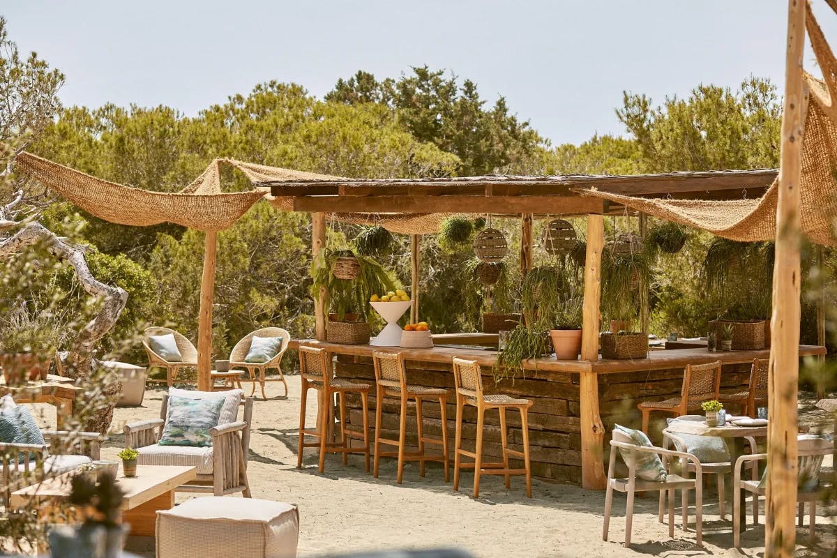 an outdoor beach patio with a breezy bar amid greenery