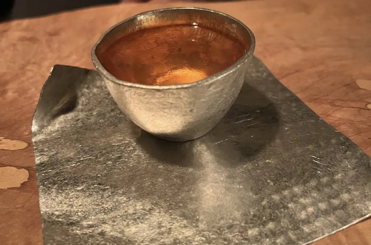 Whiskey in a steel cup sitting on a table.