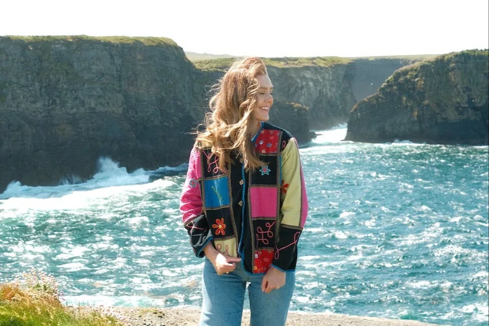 Advisor posing in front of the ocean and large cliffs while walking along the Kilkee Cliff.