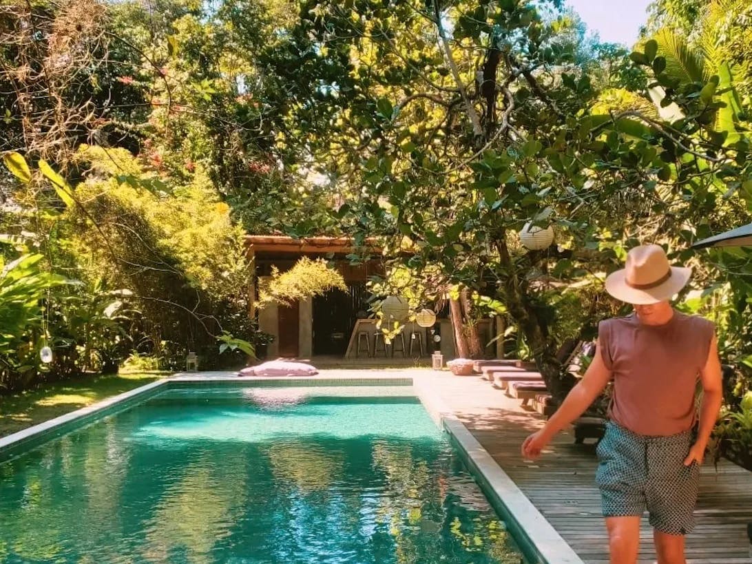 A beautiful pool area surrounded by lush greenery and a man walking alongside the pool