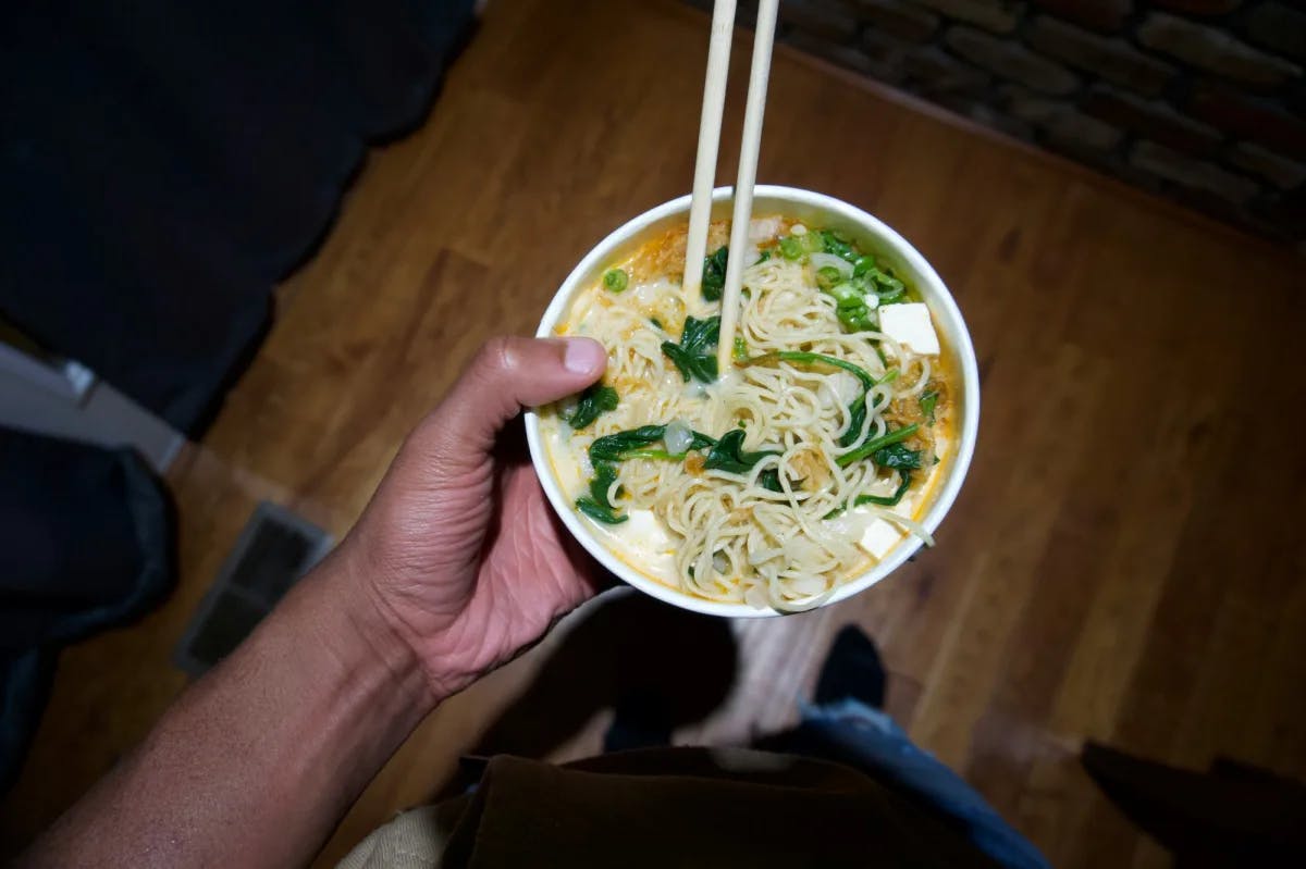 A person holding a bowl of noodles with chopsticks.