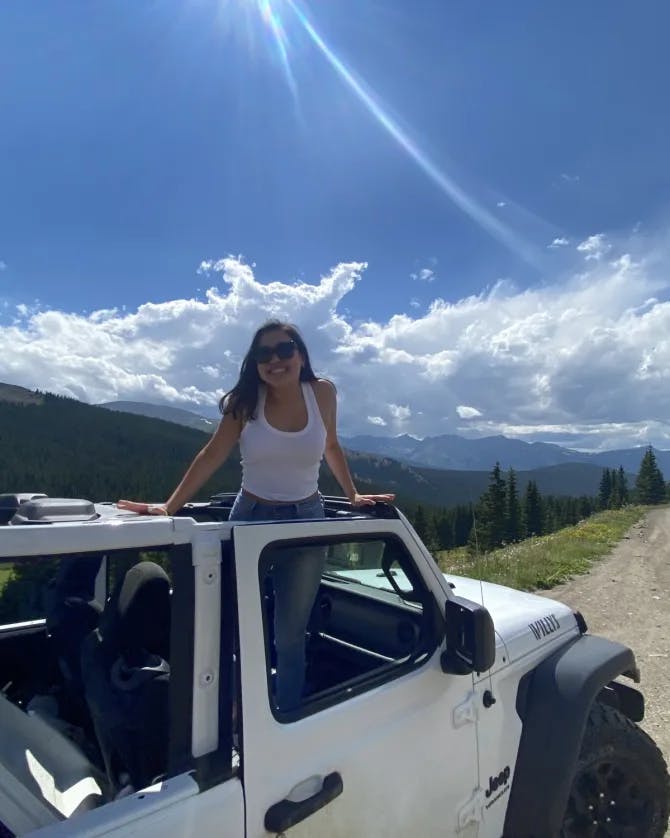 A woman standing in a white jeep.