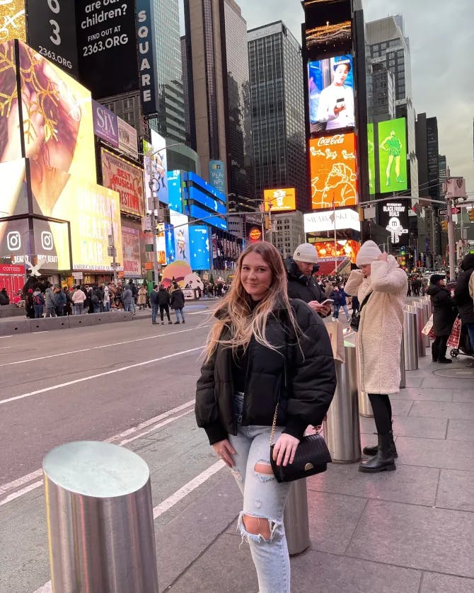 Advisor posing on a bustling corner of Time's Square on a cloudy day. 