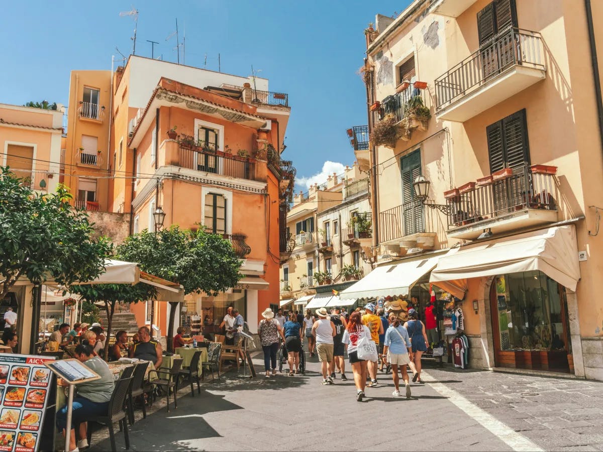 The image shows a vibrant European street scene with outdoor dining and traditional architecture.