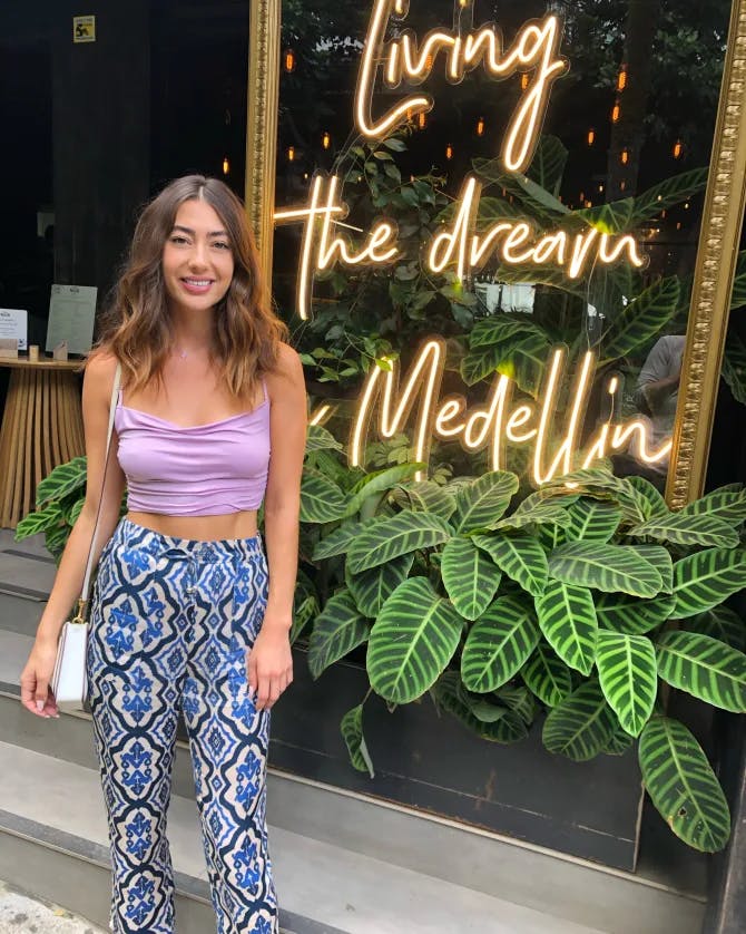 Camille on the street in front of a lighted sign reading “Living the dream in Medellín”