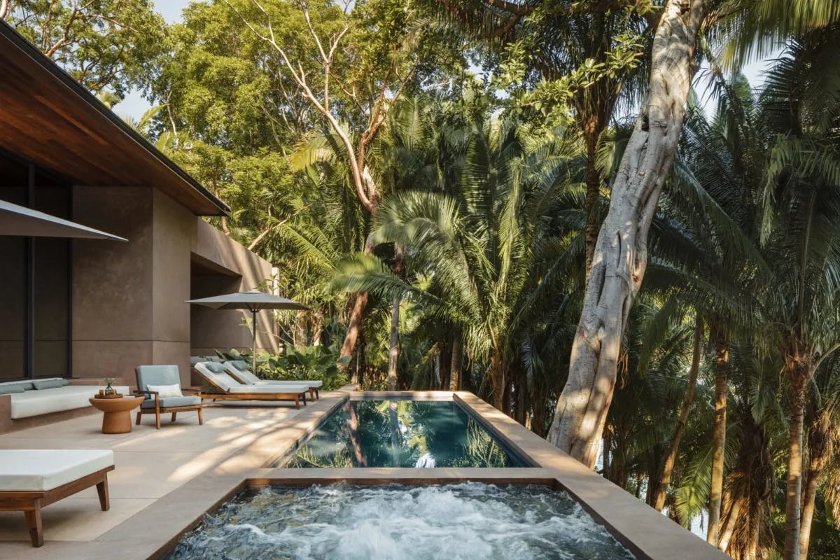 an infinity pool and a square hot tub on an elevated terrace in the jungle