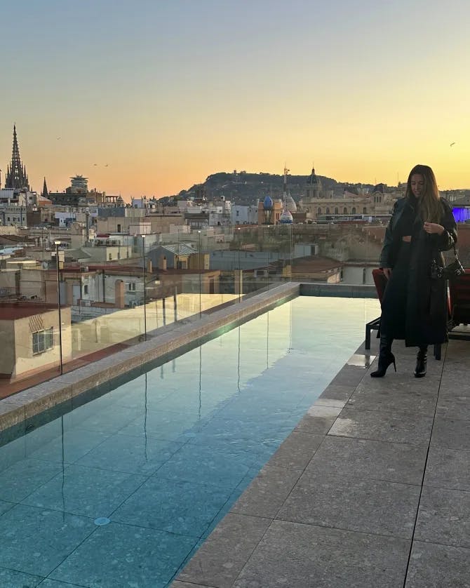 Advisor posing next to a pool overlooking a cityscape at dusk. 