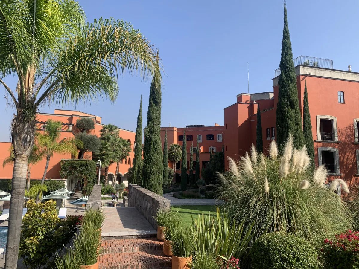 A view of the beautiful gardens and red-colored buildings of the Rosewood hotel in San Miguel de Allende