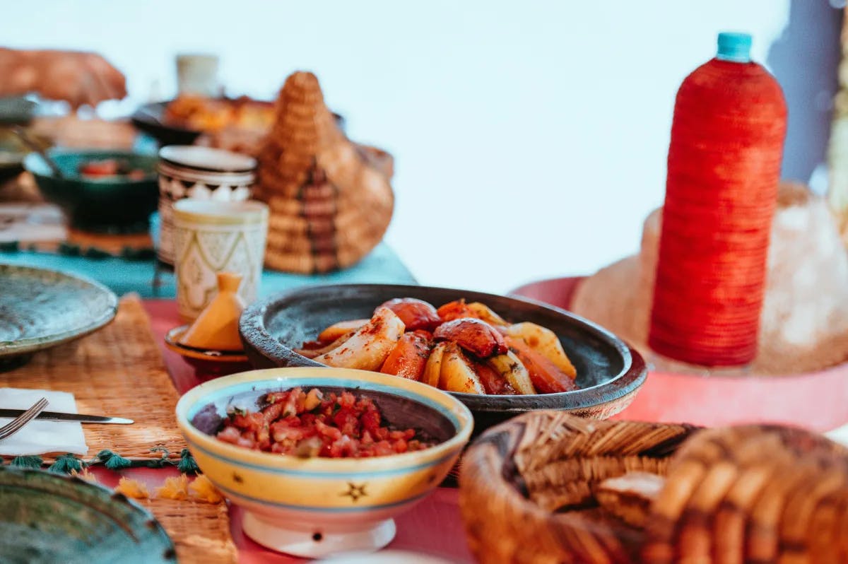 The image showcases a table of traditional Moroccan dishes with an assortment of table accessories.