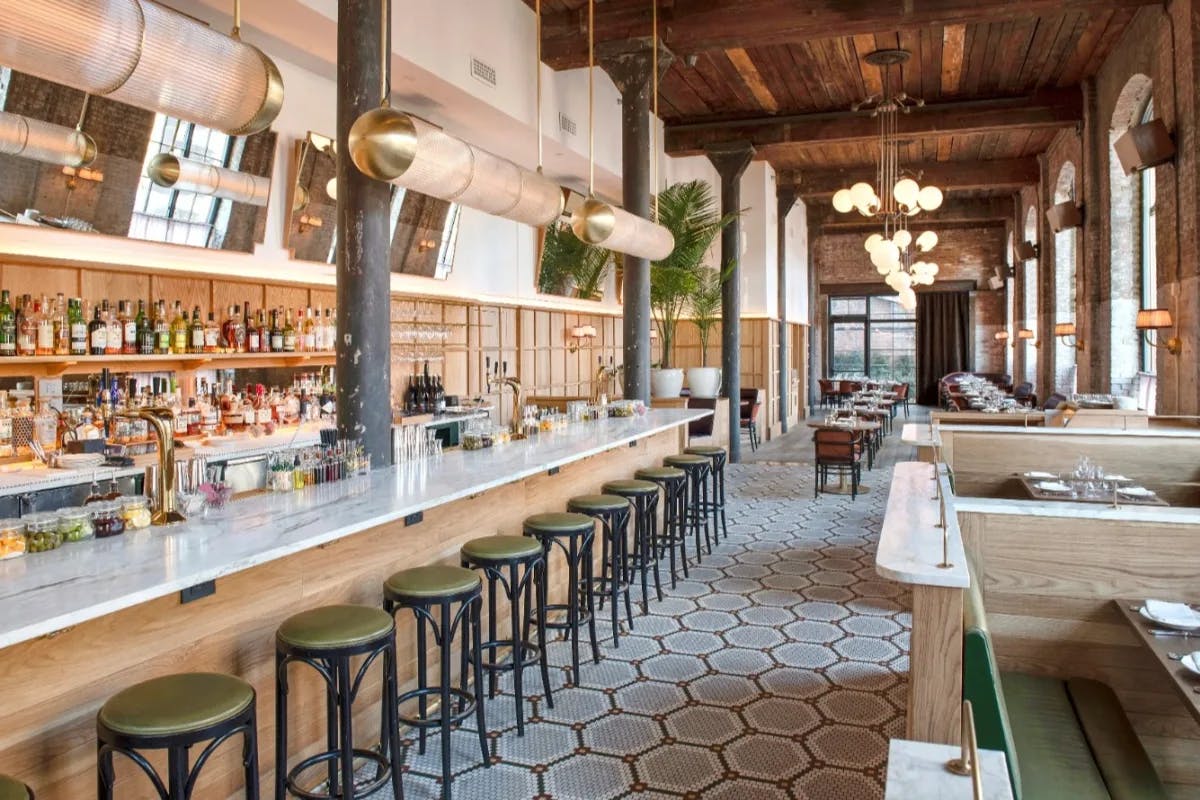 airy restaurant with long bar with stools and geometric tiled floor