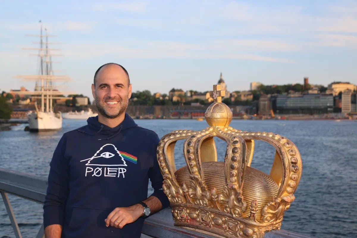 a man stands near a golden crown on the banks of an urban river