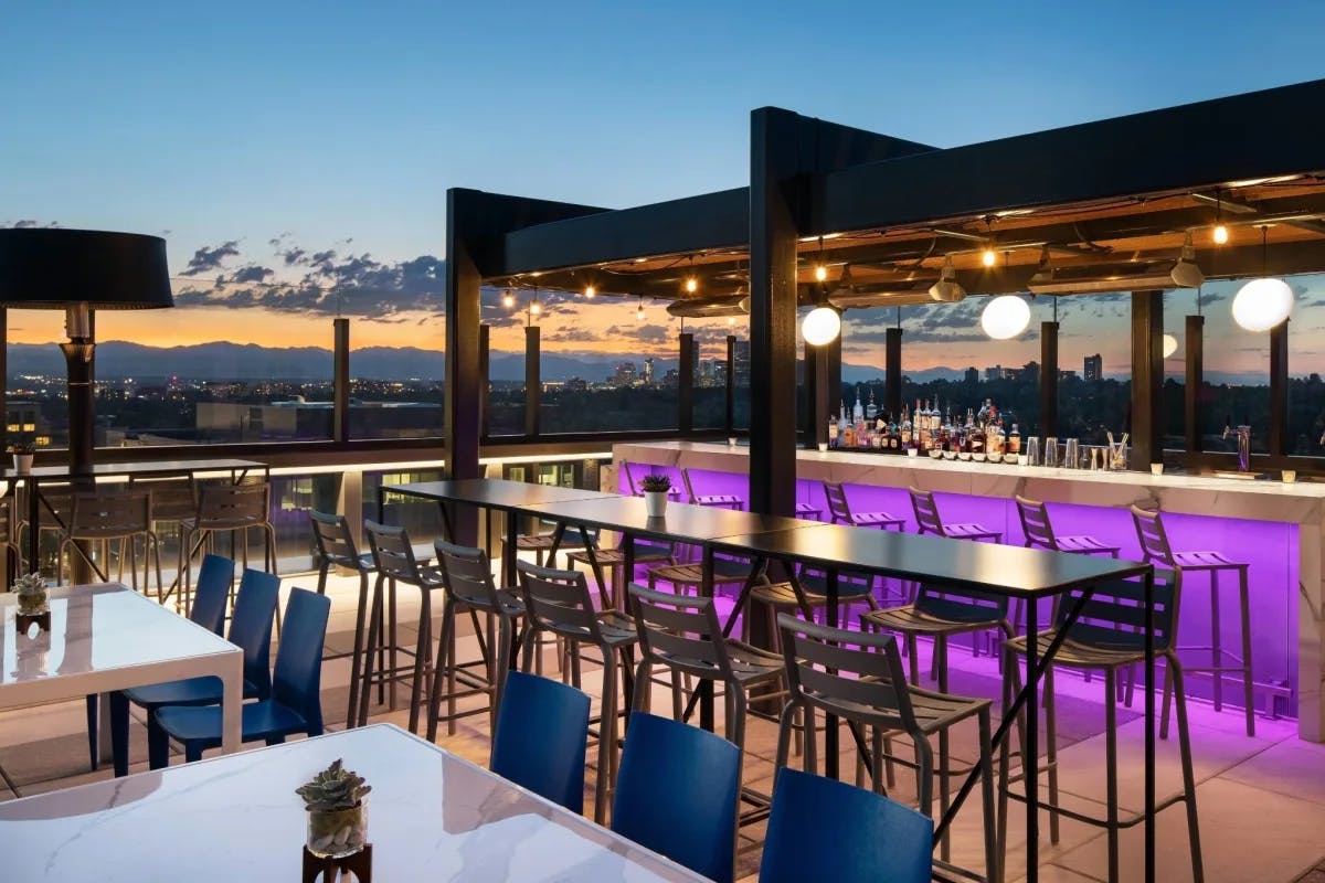 rooftop bar with tables and sunset in the distance