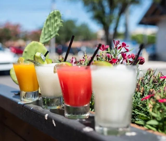 Three clear drinking glasses with orange and white cocktails. 