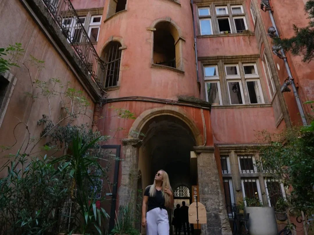 A woman in black top standing infront of a rust building.