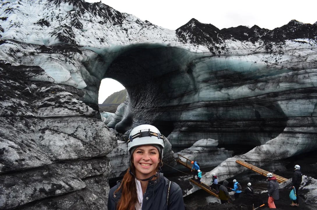 A woman in helmet in front of a cave. 