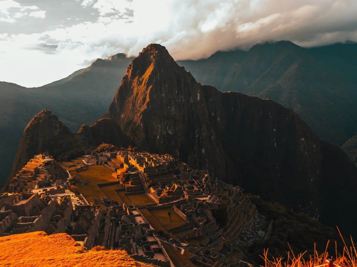 A serene snapshot of Machu Picchu bathed in the warm glow of sunset, showcasing its iconic ruins and majestic mountain backdrop.