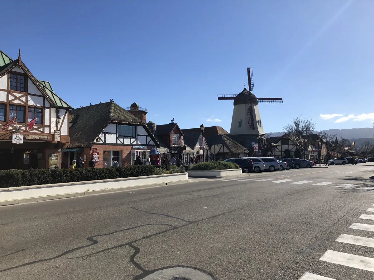 A road with European style buildings and a windmill in the background.