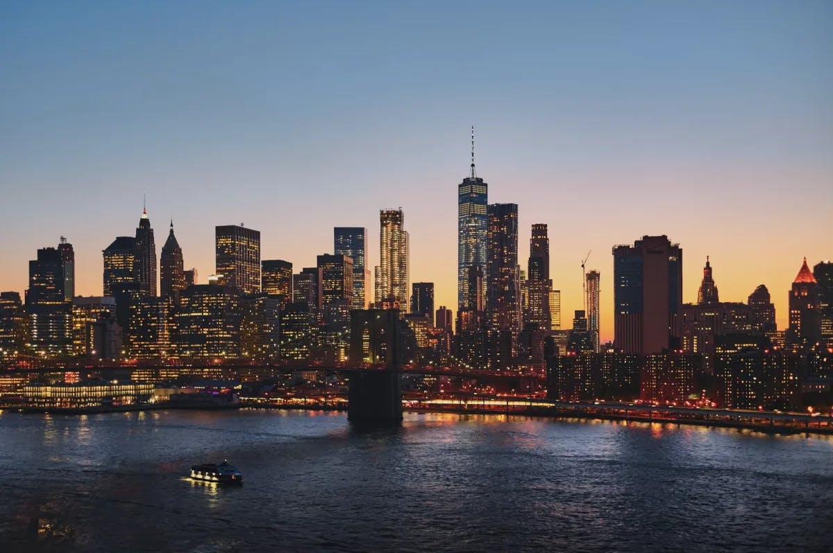 A sunset view of the New York City skyline with the river and bridge in view.