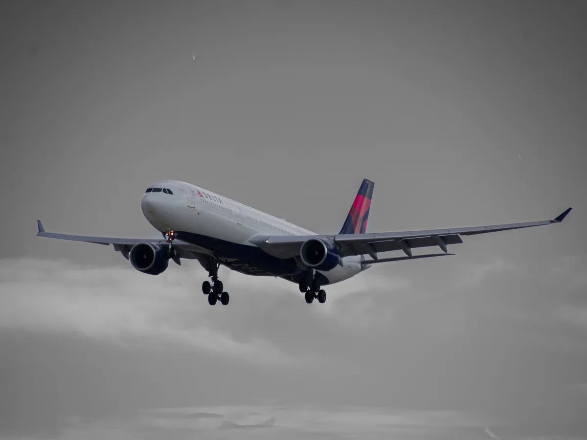 A commercial airplane soars mid-flight against a cloudy backdrop, a moment captured in ascent.