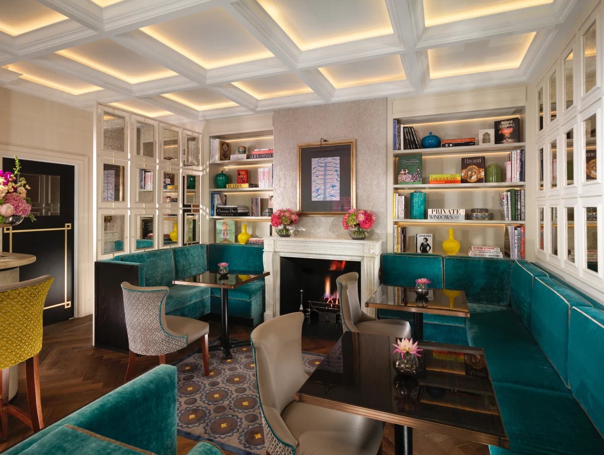 A white sitting room with bookshelves, a fireplace and blue couches