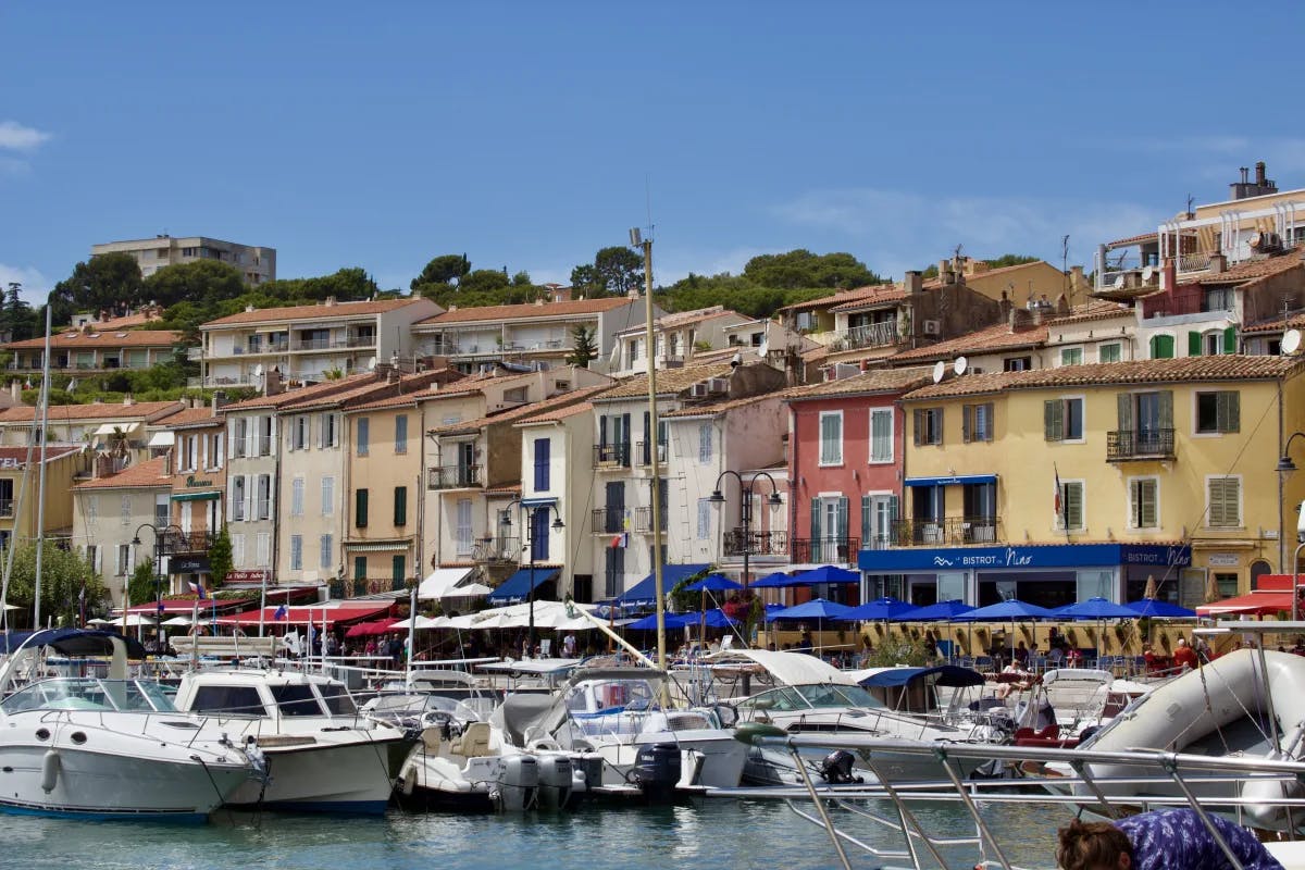 A view of multiple establishments built on the seaside that vary in color and have fishing boats docked nearby. 