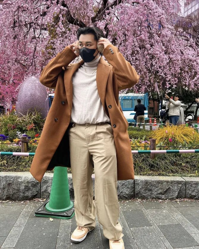 Man posing in front of vibrant flower tree