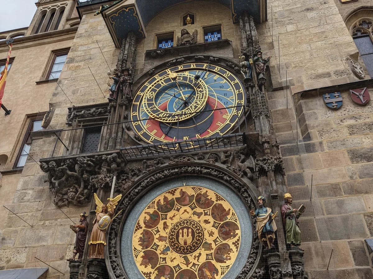 An elaborate clock on a stone building complete with various colors and gears. 