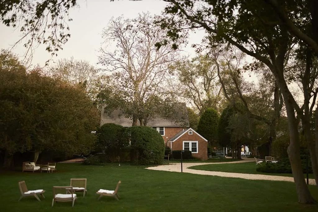 Manicured grounds and pathing lead to a quaint New England estate surrounded by fall trees