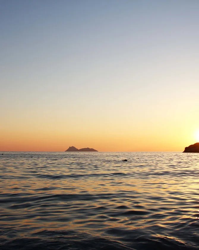 View of the sunset over the sea with an island in the distance in Greece.