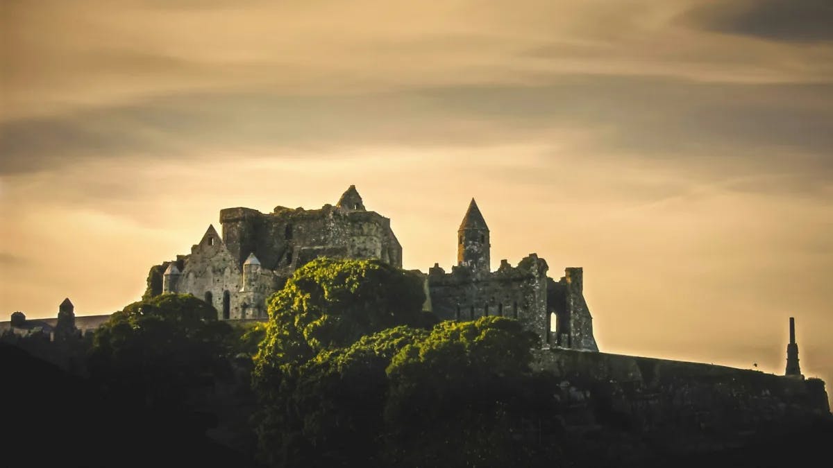Rock of Cashel, stone ruins on a hilltop at sunset.