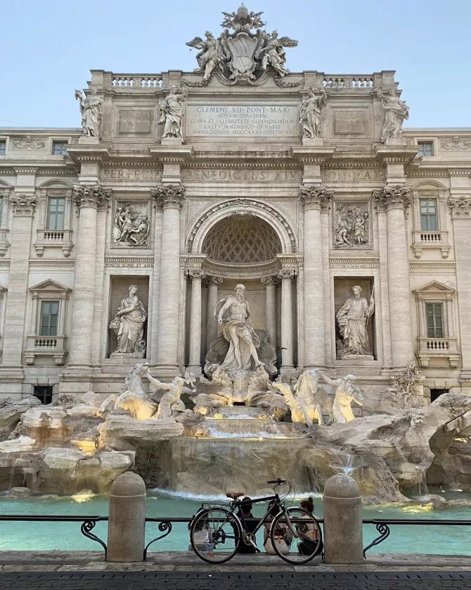 View of the Trevi Fountain in Rome with a bicycle leaning against the railing
