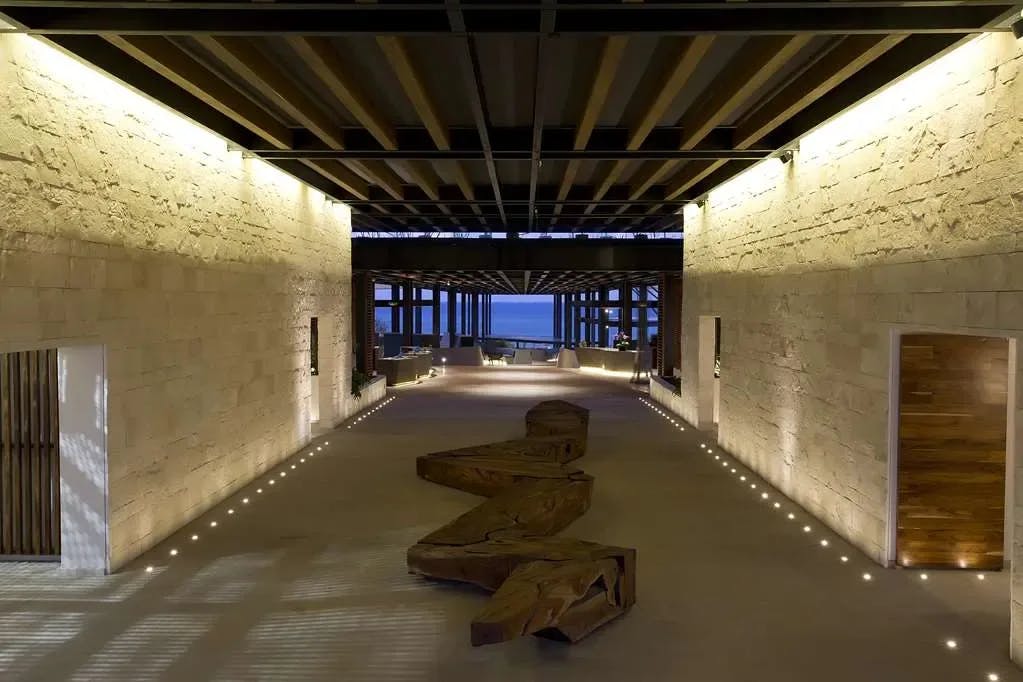 a luxe dimly lit lobby with wooden artistic benches overlooking the ocean